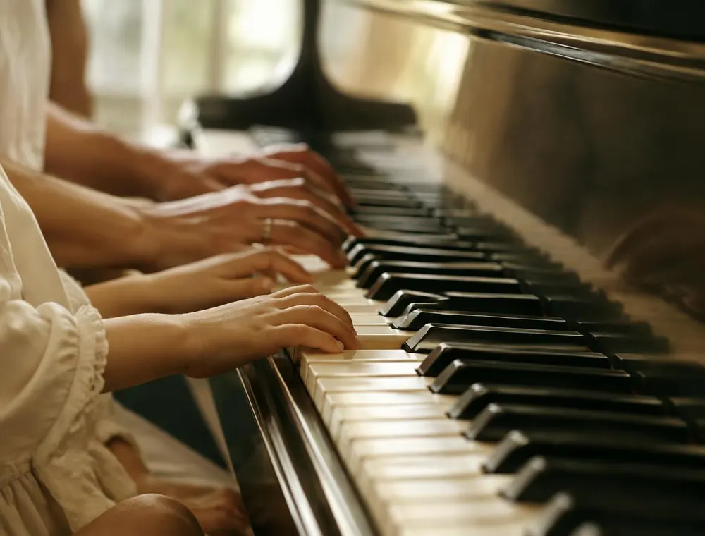 A child's hands beside an adult's on the keys during kids piano lessons in Fresno